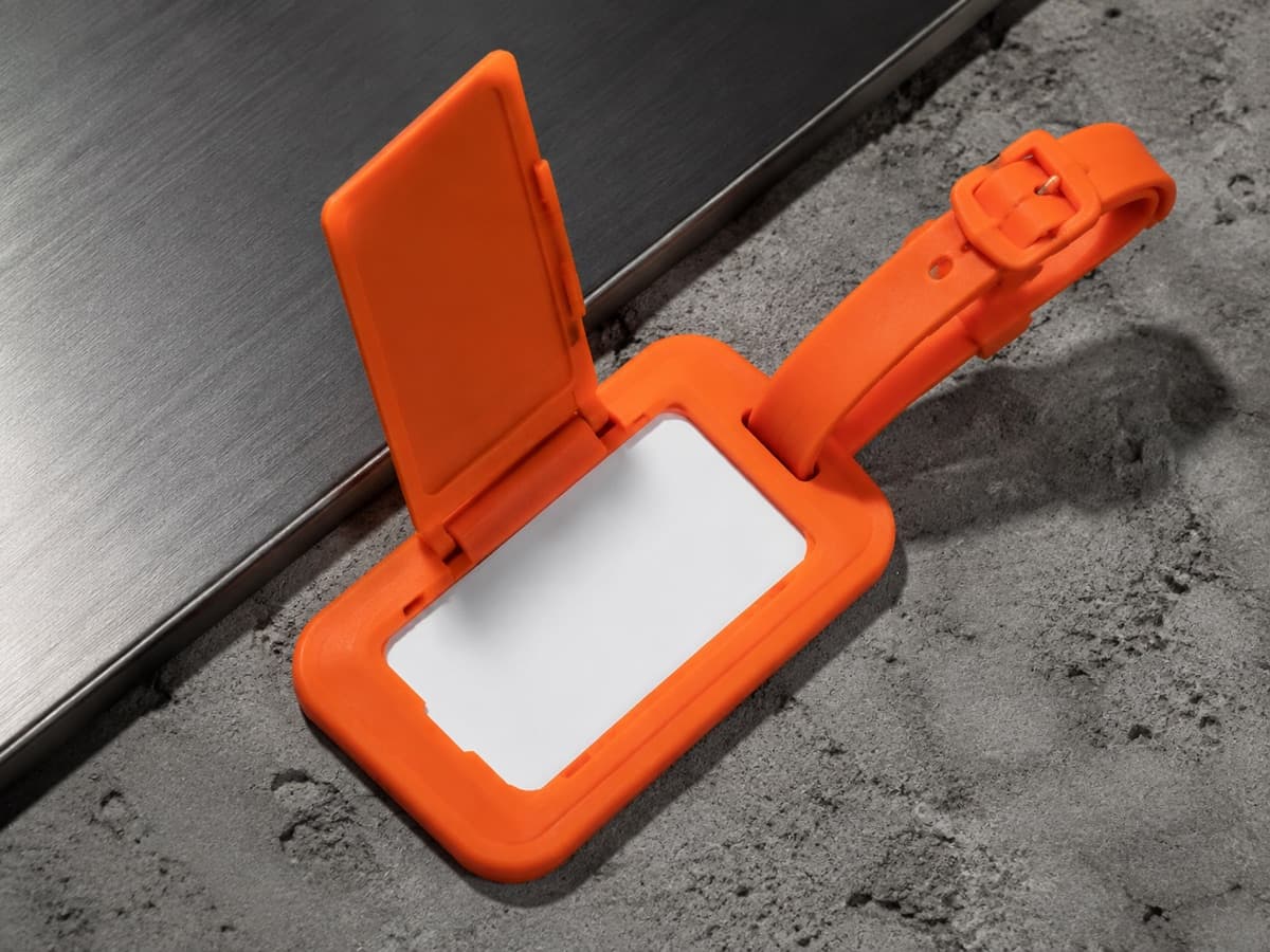 A silicone luggage tag with its privacy flap lifted to show the blank name card underneath.