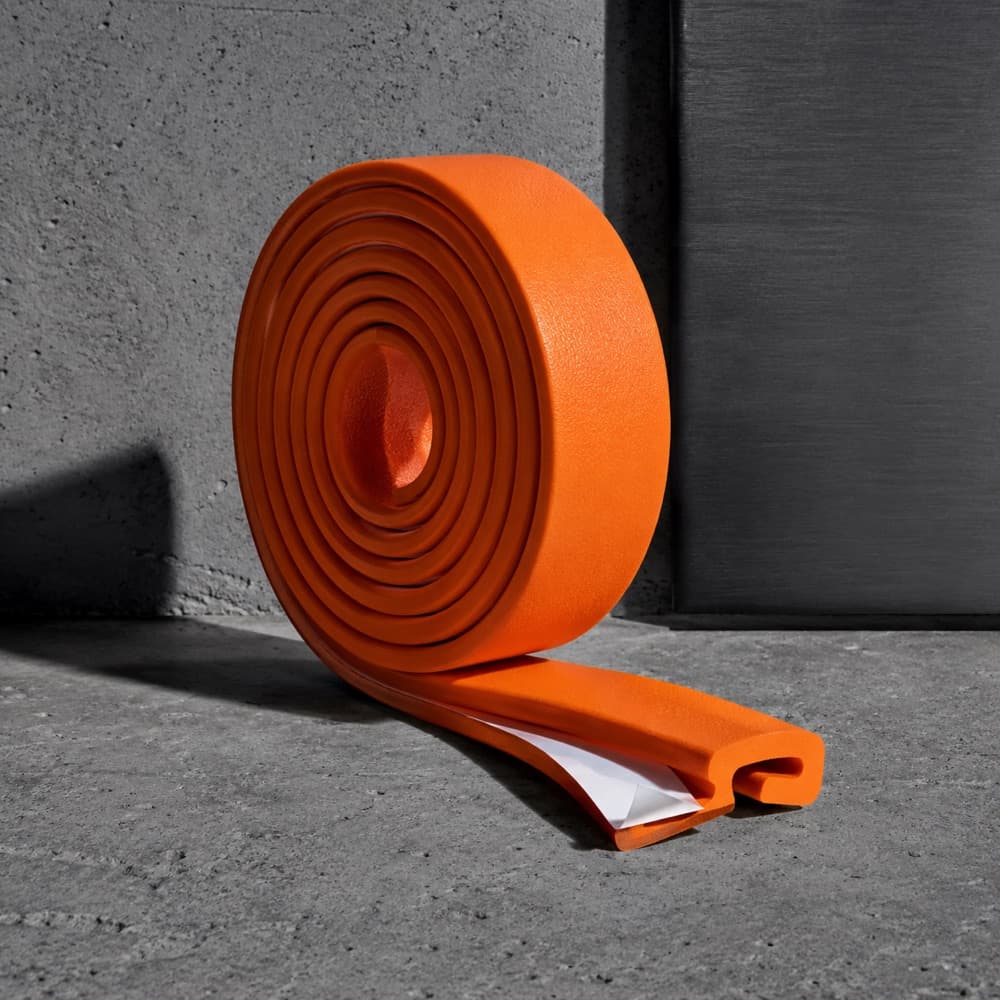 A coil of hazard-orange edge trim partly unrolled, its cut end showing the profile.