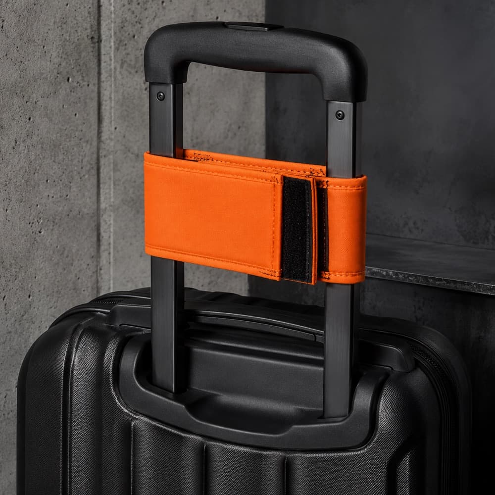 A padded wrap sleeve fastened around a telescopic case handle bar, seam visible.