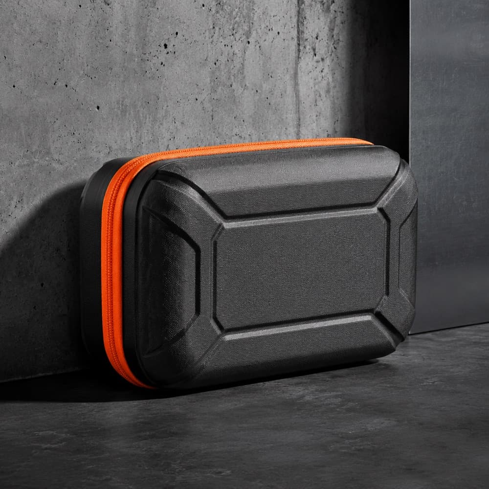 A rigid moulded protective pouch, closed, with a hazard-orange zipper around the seam.