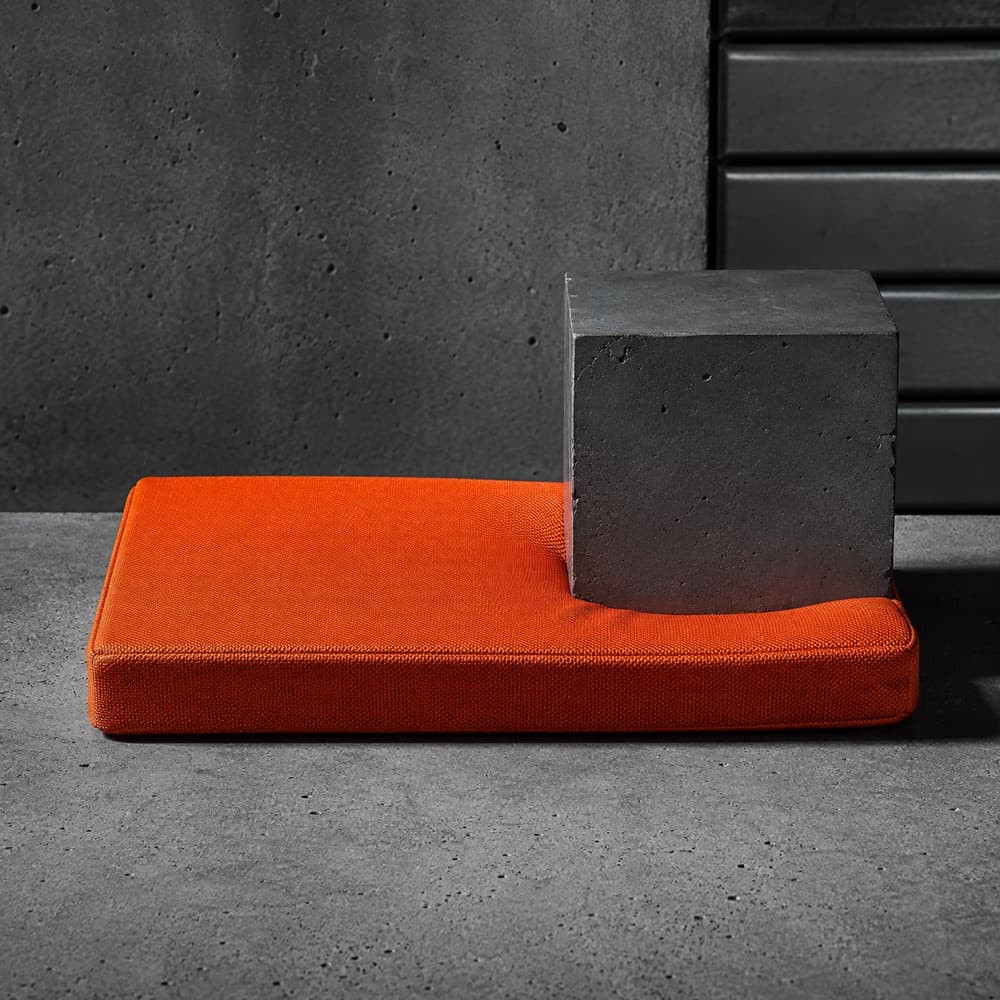 A firm rectangular fill pad with one corner compressed under a weight, thickness visible.